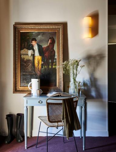 a desk with a painting of a man and a horse at Maison du Val - Les Maisons de Campagne in Saint-Germain-en-Laye
