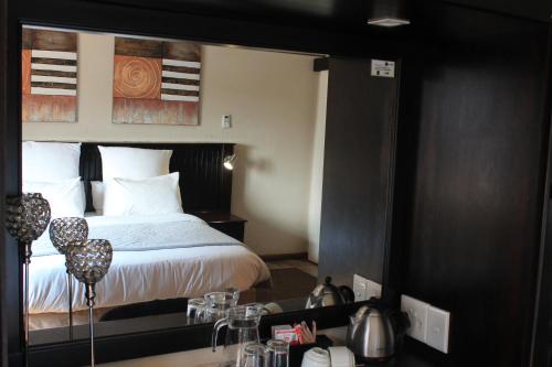 a hotel room with a bed with white sheets at Nelspruit Lodge in Nelspruit