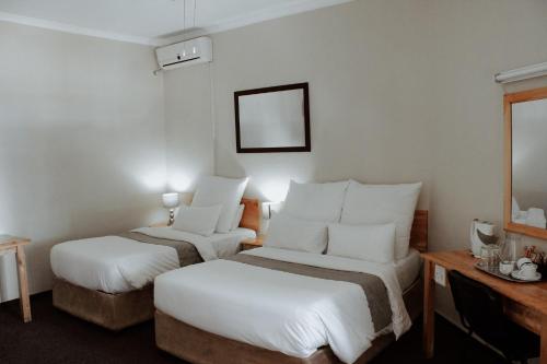 a hotel room with two beds and a mirror at Nelspruit Lodge in Nelspruit