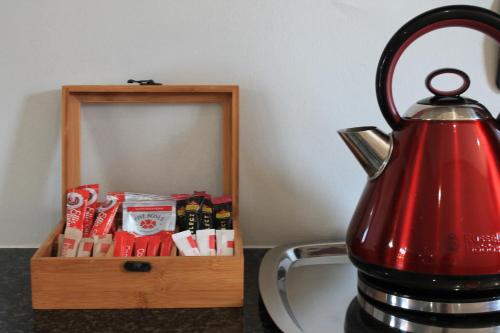 a red tea kettle sitting next to a wooden box of chocolates at Nelspruit Lodge in Nelspruit