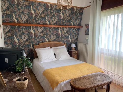 a bedroom with a bed and a wall covered in wallpaper at chambre normande in Courseulles-sur-Mer