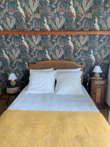 um quarto com uma cama com papel de parede floral em chambre normande em Courseulles-sur-Mer