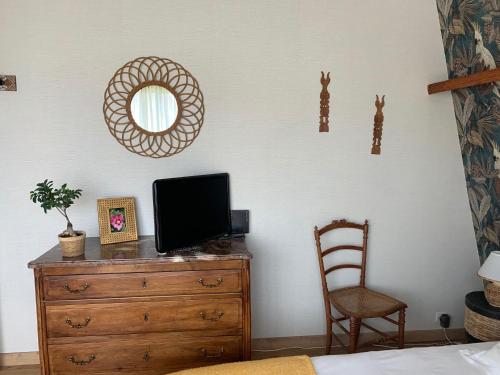 a bedroom with a dresser and a mirror and a chair at chambre normande in Courseulles-sur-Mer