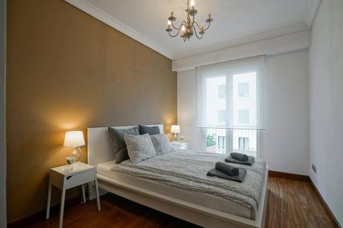 a bedroom with a bed with a chandelier and a window at AMPLIO APARTAMENTO en GROS con PARKING PRIVADO in San Sebastián