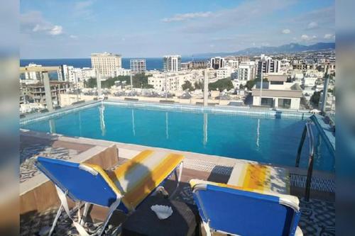 a swimming pool and two chairs on a roof at Aqua Royal Holiday Apartments Girne in Kyrenia