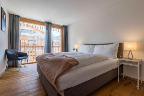 a bedroom with a bed and a large window at Montela Apartment-Hotel & Resort in the holiday region Saas-Fee Saastal in Saas-Grund