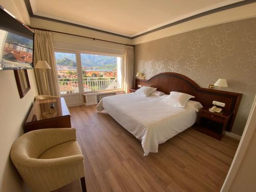 a bedroom with a bed and a chair and a window at Gran Hotel del Sella in Ribadesella