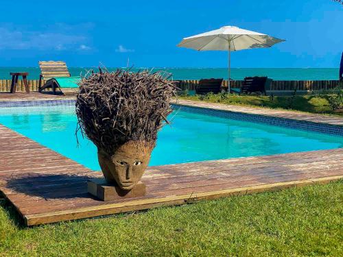 une statue à tête assise à côté d'une piscine dans l'établissement Pousada Villa Tatuamunha, à Porto de Pedras