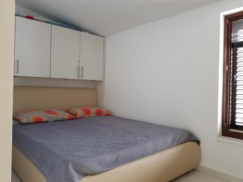 a bedroom with a bed with white cabinets and a window at Relax Zone III in Malinska