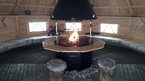 a fireplace in the middle of a cabin with windows at Karemajat Panorama hotel in Ylitornio