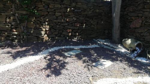 a dog laying on the ground next to a stone wall at Appartamento Ercole in Budoni