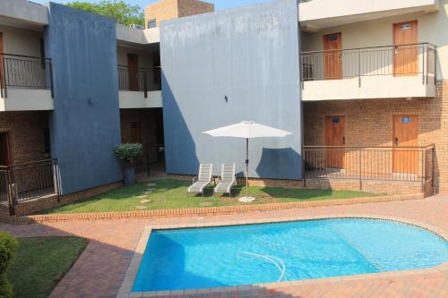 a swimming pool in front of a building with an umbrella at Nelspruit Lodge in Nelspruit