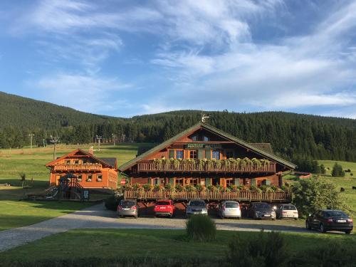a large wooden building with cars parked in front of it at Penzion Haltmar in Ostružná