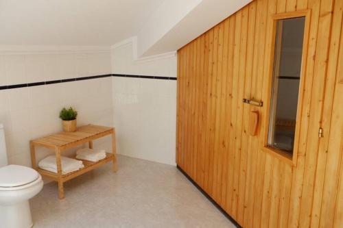 a bathroom with a toilet and a wooden door at Duplex precioso con jacuzzi, sauna y chimenea . in Ochandiano