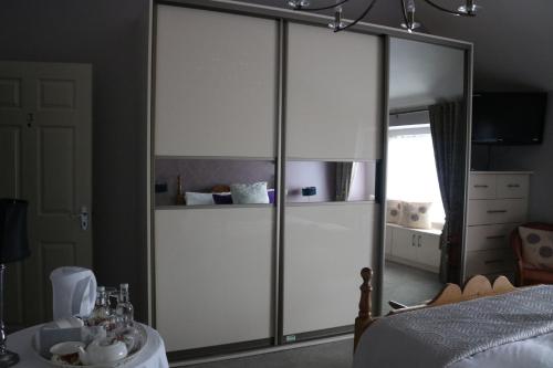 a bedroom with a large white closet with glass doors at New Park Hotel Athenry in Athenry