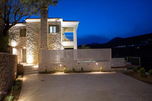 a house with a lit up driveway at night at Villa Anthelia-Idyllic view and private access to the sea in Sivota