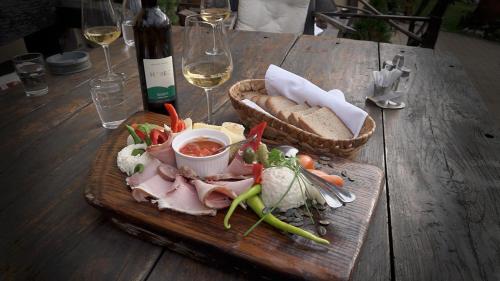 a wooden table with a plate of food and a glass of wine at Urlaub für die Seele - Erholung Pur in der Natur - Ferienhaus mit Infrarotkabine & RELAX-Raum in Rucmanci