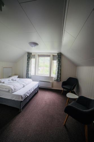 a bedroom with a bed and a chair and a window at Gudvangen Budget Hotel in Gudvangen