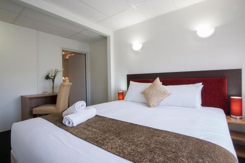 a bedroom with a large white bed and a desk at Ascotia Off Queen in Auckland