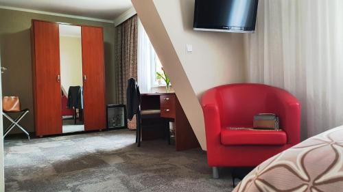 a bedroom with a red chair and a desk at Hotel Atlas Halle in Halle an der Saale