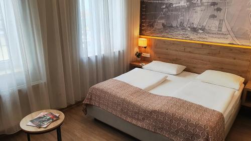 a bedroom with a bed and a table and a picture at Hotel Atlas Halle in Halle an der Saale