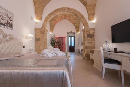 a bedroom with a bed and a desk and a television at Donna Fiora Antica Dimora in Alliste