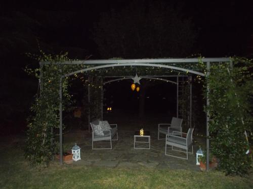a gazebo with chairs and a fire in a yard at night at La Bella Vite in Moncalvo