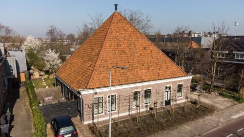 un vieux bâtiment avec un toit orange dans une rue dans l'établissement Traditional family apartment with garden at countryside Amsterdam, à Landsmeer