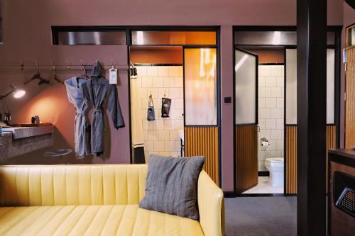 a living room with a yellow couch and a bathroom at URSIDE Hotel Shanghai The Bund in Shanghai
