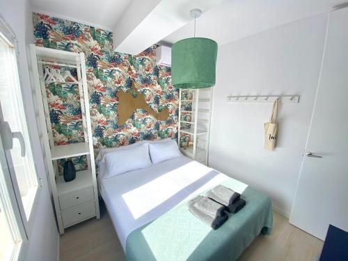 a small bedroom with a bed and a floral wall at Appartement NoBe Es Pujols proche plage, vue mer in Es Pujols