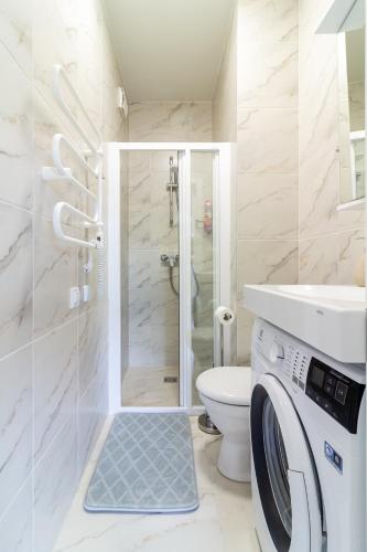 a bathroom with a shower toilet and a washing machine at VineWood Apartment, By Cohost in Palanga