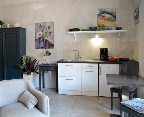 - une cuisine avec des placards blancs, un évier et un canapé dans l'établissement les Lauriers, à Caromb