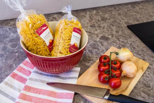 a bowl of pasta and tomatoes on a cutting board at STAUDACH - Alpinresidenz Zillertal in Ramsau im Zillertal