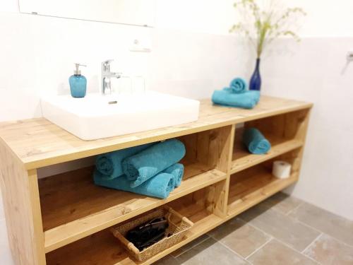 ein Badezimmer mit einem Waschbecken und Handtüchern auf einem Holzregal in der Unterkunft Haus Leitner in Attersee am Attersee