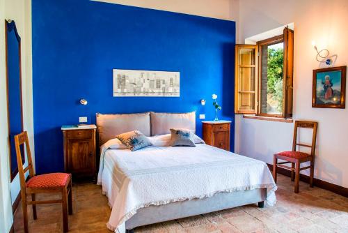 a blue bedroom with a bed and two chairs at BOSSONCINA 8&1, Emma Villas in Montepulciano