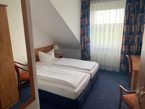 ein kleines Schlafzimmer mit einem Bett und einem Fenster in der Unterkunft Hotel Dülmener Hof in Dülmen