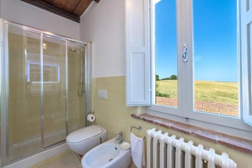 baño con aseo y lavabo y ventana en CASALE BONAVENTURA 8, Emma Villas, en Ostra