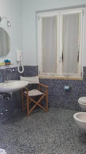 a bathroom with two sinks and a chair and a shower at VILLA FLORA ARGENTARIO in Porto Santo Stefano