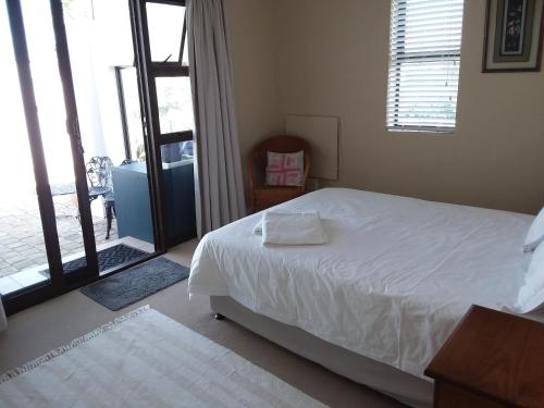 1 dormitorio con 1 cama y puerta corredera de cristal en Trev's Place, en St Francis Bay