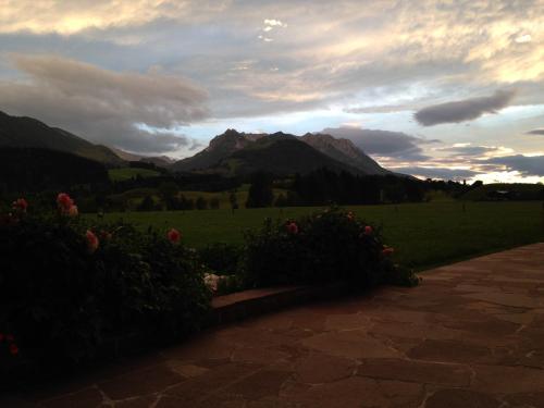 a sunset over a field with mountains in the background at Bio-Bauernhof Bachangerhof in Kössen