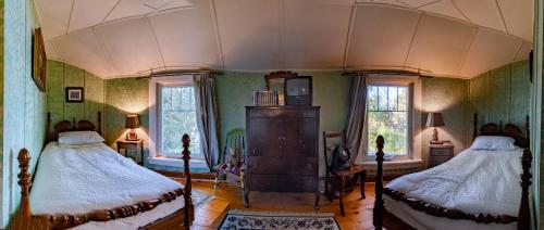 a bedroom with two beds and two windows at Windswept on the Trent in Campbellford