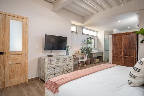 Schlafzimmer mit einem Bett, einem TV und einem Schreibtisch in der Unterkunft Casa Pandurata Luxury Apartments in Centro, San Miguel de Allende in San Miguel de Allende