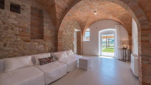 a living room with a white couch in a brick wall at Dimora Montefiore 11, Emma Villas in Montefiore dellʼAso