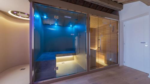 um chuveiro de vidro com luzes azuis num quarto em Dimora Montefiore 11, Emma Villas em Montefiore dellʼAso