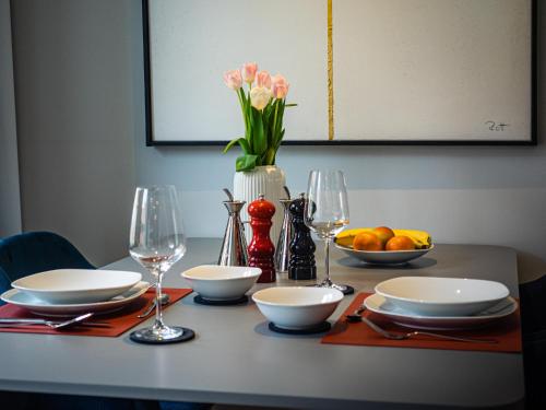 a table with plates and glasses and a vase with flowers at Swebenhus boven - FeWo mit großer Dachterrasse in Plau am See