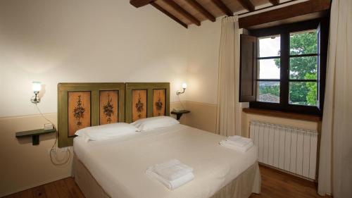 ein Schlafzimmer mit einem weißen Bett und einem Fenster in der Unterkunft IL BORGO 16, Emma Villas in Assisi