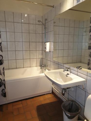 a bathroom with a sink and a tub and a mirror at Mehamn Arctic Hotel in Mehamn