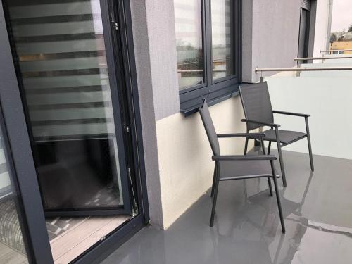 two chairs sitting on a balcony with windows at Apartament Plaza Premium in Słupca
