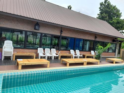 un edificio con mesas y sillas junto a una piscina en Paiberngboc Resort en Ban Na Phoc Thap