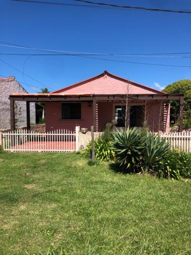 a red house with a fence in the yard at Casa rosa - se reserva con seña in Barra del Chuy